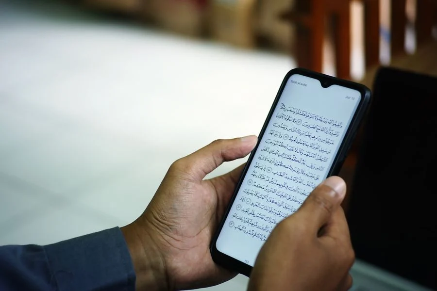 Hands practising Qur’an recitation on a phone